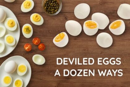Hard-boiled eggs cut in half on a wooden table, some filled with classic deviled egg filling and others waiting to be prepared.